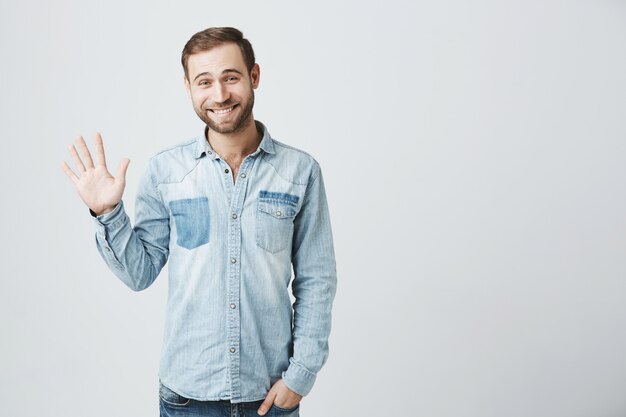 Bescheidener niedlicher bärtiger Mann sagen Hallo, winkend Hand zur Begrüßung