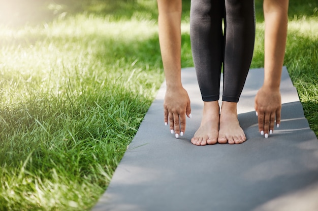 Beschnittener Schuss der Frau, die Pilates oder Yoga oder Übungen im Park tut. Hände und Füße auf Yogamatte gepflanzt.
