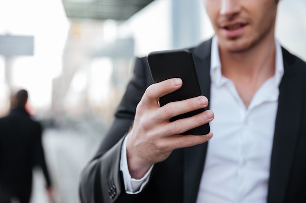 Beschnittenes Bild des glücklichen jungen Geschäftsmannes, der per Telefon plaudert.