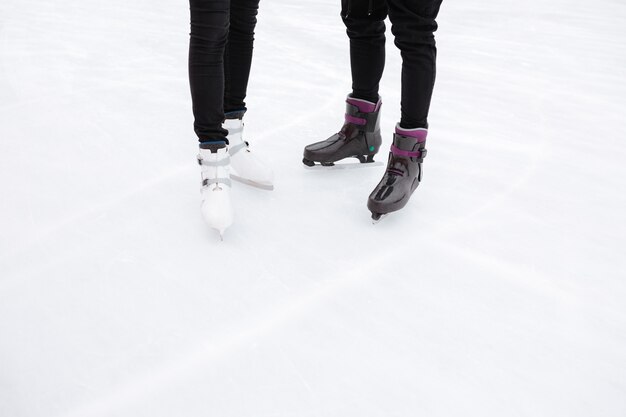 Beschnittenes Bild des jungen liebenden Paares, das an der Eisbahn skatet