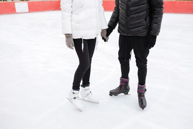 Beschnittenes Bild des jungen liebenden Paares, das an der Eisbahn skatet