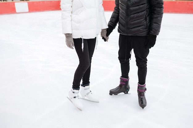 Beschnittenes Bild des jungen liebenden Paares, das an der Eisbahn skatet