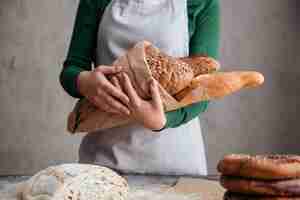 Kostenloses Foto beschnittenes bild des weiblichen bäckers, der tasche mit brot hält