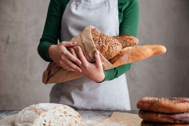 Beschnittenes Bild des weiblichen Bäckers, der Tasche mit Brot hält