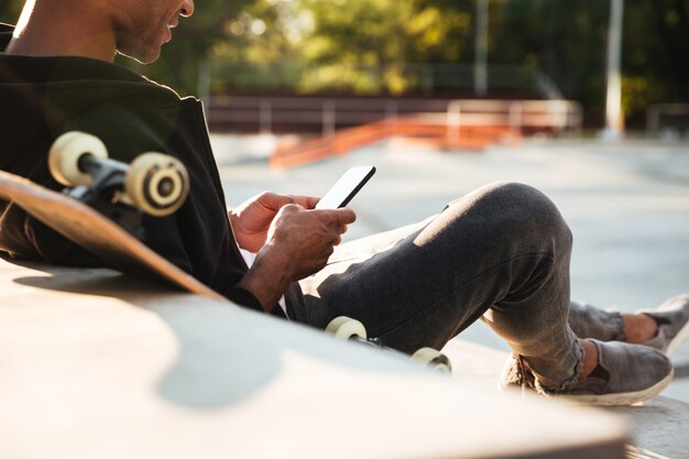 Beschnittenes Bild eines afrikanischen Kerls unter Verwendung des Mobiltelefons