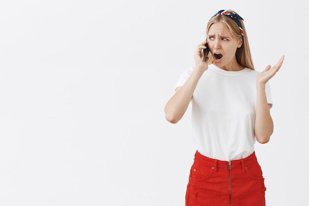 Kostenloses Foto besorgt schockiert junges blondes mädchen posiert gegen die weiße wand