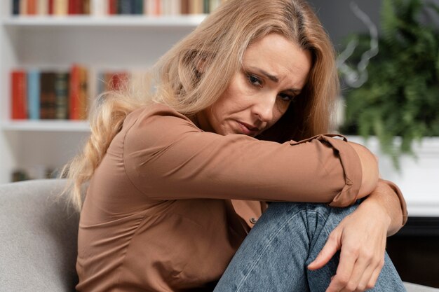 Besorgte blonde Frau sitzt auf der Couch