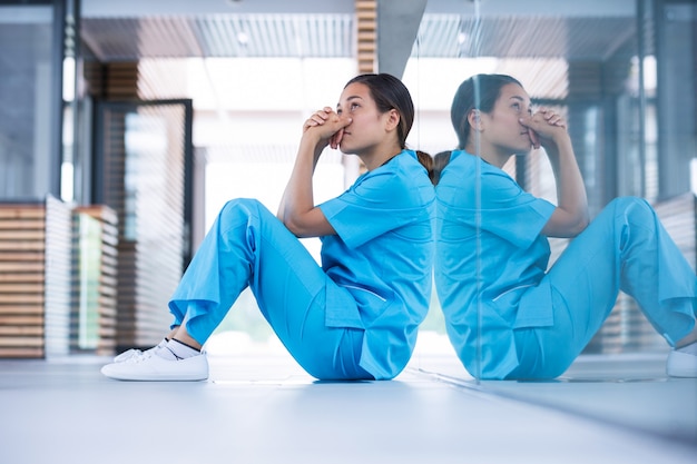 Besorgte krankenschwester sitzt auf dem boden