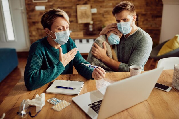 Besorgte Mutter, die während der Coronavirus-Pandemie einen Videoanruf mit einem Arzt von zu Hause aus führt