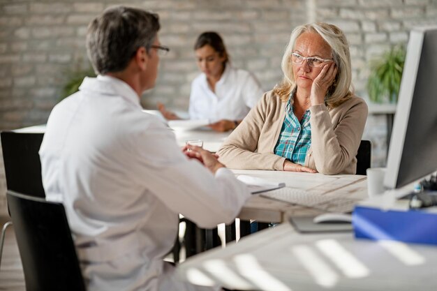 Besorgte reife Frau, die während der Beratung in der Klinik mit medizinischem Personal über Krankenversicherung spricht