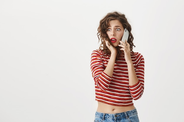 Besorgte und schockierte attraktive Frau reagieren auf schlechte Nachrichten per Telefonanruf