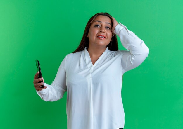 besorgte zufällige kaukasische Frau mittleren Alters, die Telefon hält und Hand auf Kopf legt