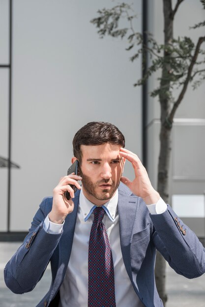 Besorgter Geschäftsmann, der am Telefon spricht