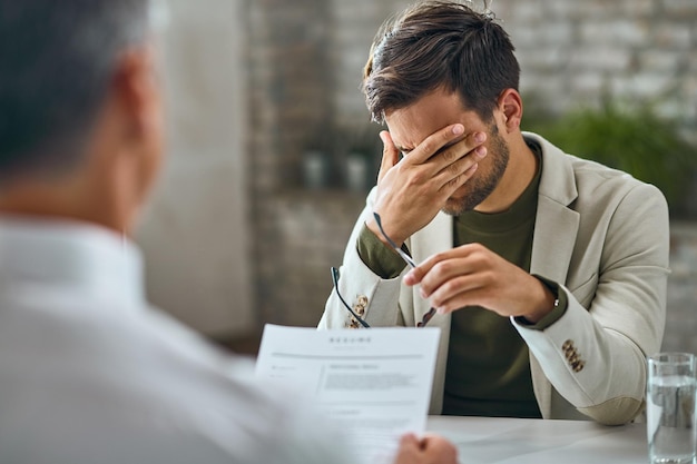 Kostenloses Foto besorgter männlicher kandidat, der ein vorstellungsgespräch mit einem manager im büro hat