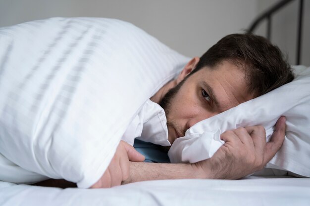Besorgter Mann, der im Bett liegt, mittlerer Schuss