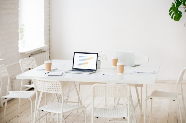 Besprechungstisch mit Laptops und Kaffee im leeren Büroraum