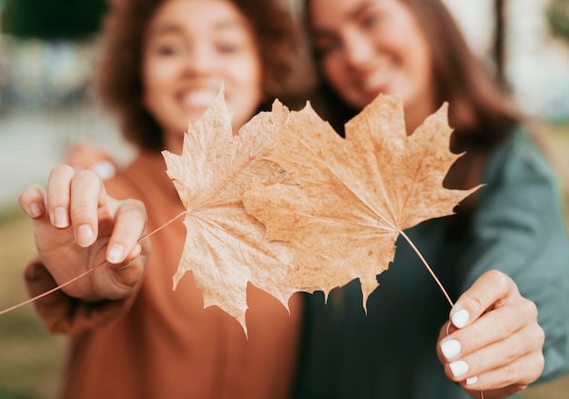 Kostenloses Foto beste freunde, die herbstlaub halten