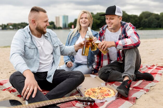 Beste Freunde jubeln mit Bierflaschen am Strand