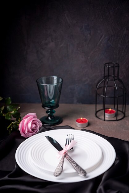 Besteck auf Tellern mit Rose und Kerzen
