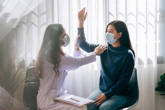 Besuch eines asiatischen Arztes und Untersuchung einer jungen erwachsenen Frau im Krankenhaus mit Symptom des Bürosyndroms