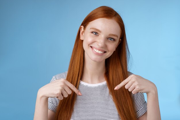 Besuchen Sie einen Ort, den Sie lieben. Freundlich aussehende freundliche, sanfte, attraktive rothaarige Frau, die Werbekopienraum zeigt und Zeigefinger nach unten neigt, den Kopf lächelt hilfreich empfehlen Promo