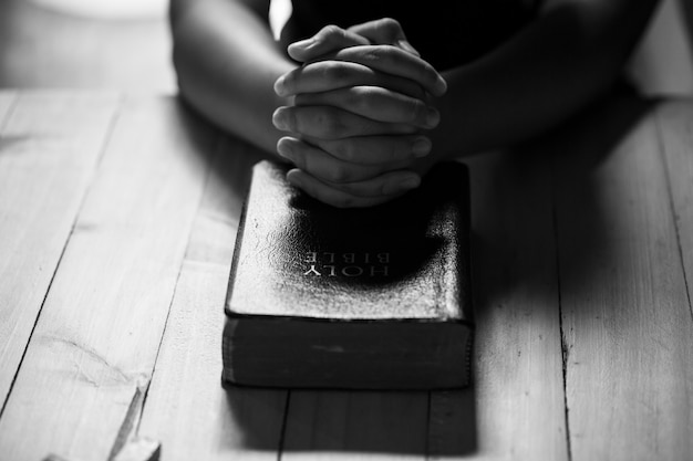 Betende Hände des Teenagers auf alter Bibel
