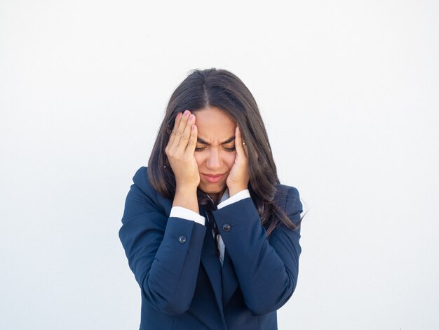 Betonte frustrierte Geschäftsfrau, die unter Kopfschmerzen leidet