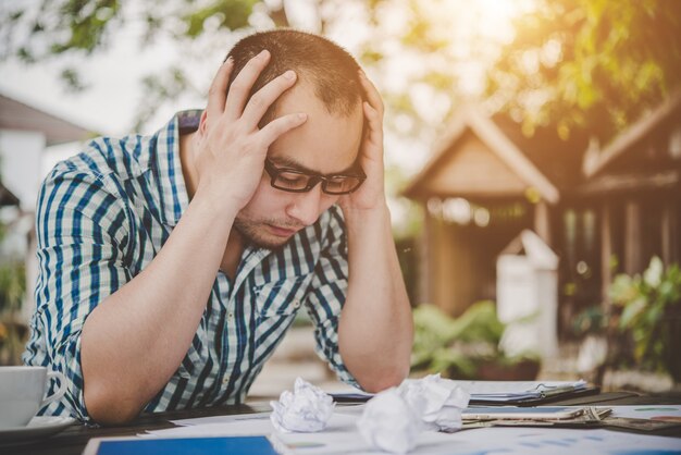 Betonter Geschäftsmann mit Papieren und Charts sitzt am Tisch zu Hause. Geschäftsmann mit Papierkram und Deadline-Konzept.