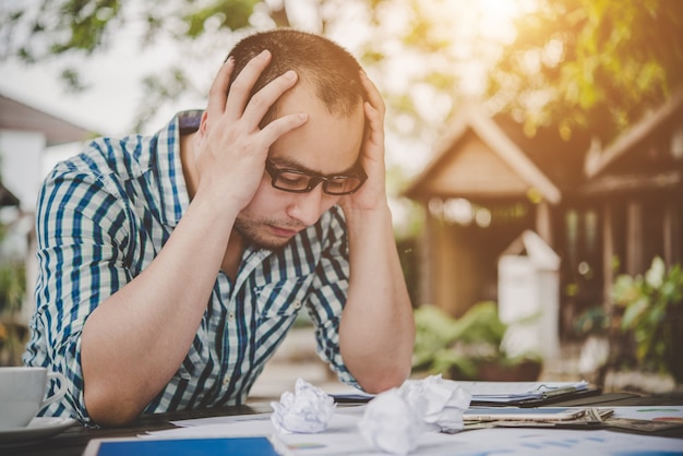 Betonter Geschäftsmann mit Papieren und Charts sitzt am Tisch zu Hause. Geschäftsmann mit Papierkram und Deadline-Konzept.