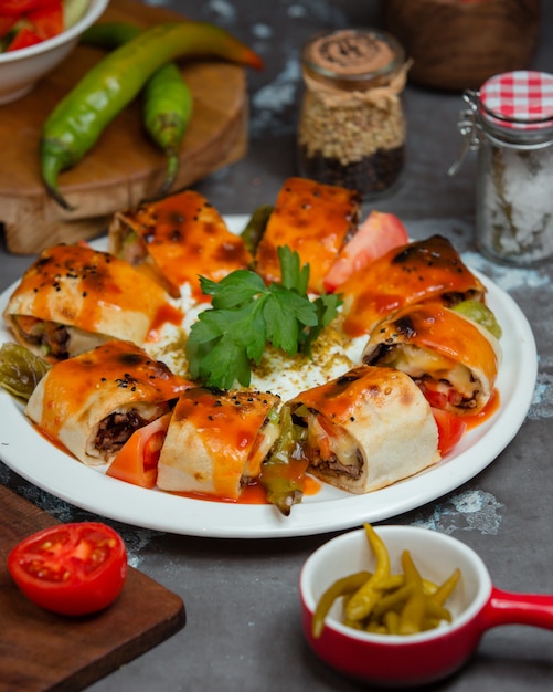 Beyti-Kebab-Brötchen, serviert in Fladenbrot mit geröstetem Gemüse und Tomatensauce