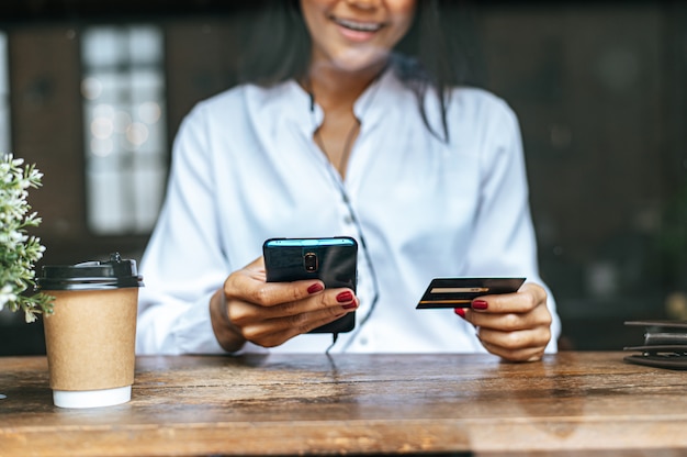 Bezahlen Sie Waren mit Kreditkarte über ein Smartphone in einem Café.