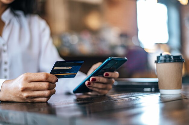 Bezahlen Sie Waren mit Kreditkarte über ein Smartphone in einem Café.