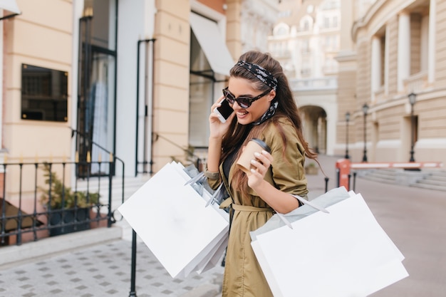 Bezaubernde Fashionista-Frau, die am Telefon spricht und im Herbstwochenende lächelt