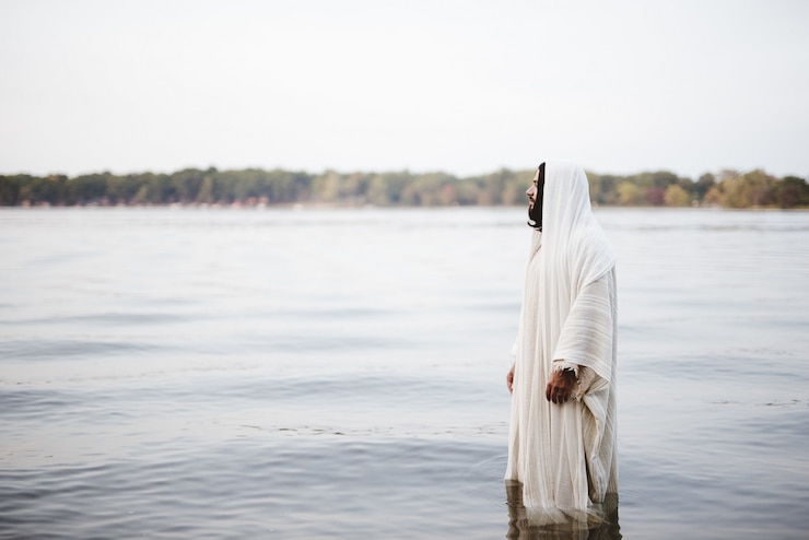 Kostenlose Foto biblische szene - von jesus christus, der im wasser mit einem unscharfen hintergrund steht