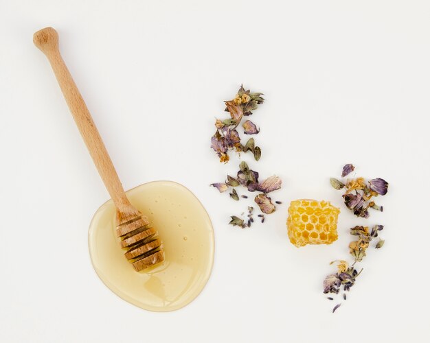 Bienenwabe zwischen Trockenblumen mit hölzernem Schöpflöffel