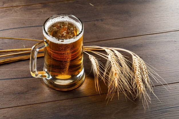 Bier in einem Glasbecher mit Weizenohren hoher Winkelansicht auf einem Holztisch