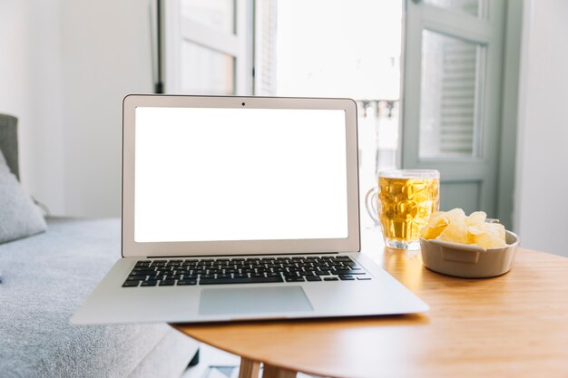 Bier und Kartoffelchips nahe Laptop