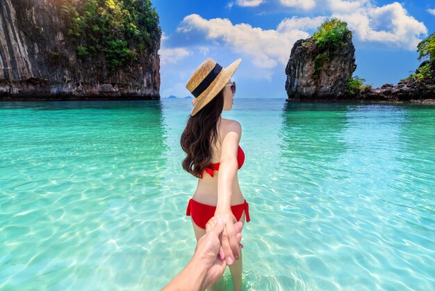 Bikini-Mädchen, das die Hand des Mannes hält und ihn zur Insel Koh Hong in Krabi, Thailand, führt