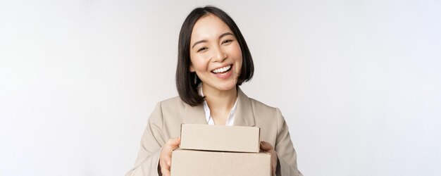 Bild der asiatischen Verkäuferin Geschäftsfrau, die Kisten mit Bestellung gibt, liefern an den Kunden, der im Anzug auf weißem Hintergrund steht
