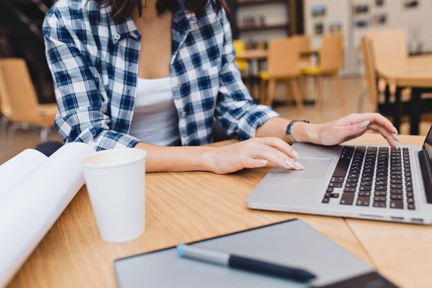 Bild der jungen Frau, die mit Laptop auf Tisch arbeitet, um kreatives Zeug zu umgeben. Freiberufler, kluger Student, moderne Zeit, im Internet arbeiten, suchen, surfen.