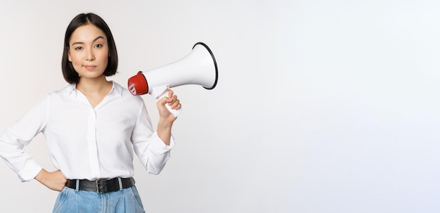 Bild der modernen asiatischen Frau mit dem Megaphon, das weißen Hintergrund der Ankündigung macht