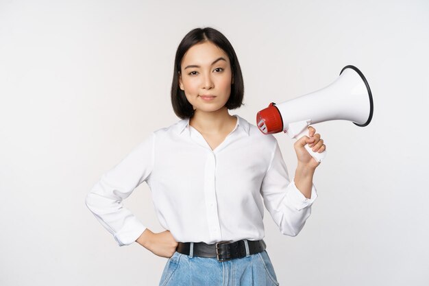 Bild der modernen asiatischen Frau mit dem Megaphon, das weißen Hintergrund der Ankündigung macht