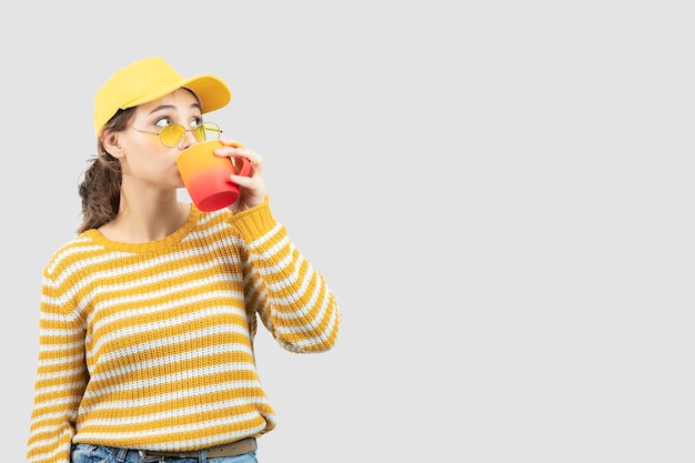 Bild der netten jungen Frau in den Gläsern, die aus einer Tasse stehen und trinken. Foto in hoher Qualität