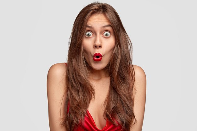 Bild der schockierten grünäugigen jungen Frau hält Mund rund, hat roten Lippenstift