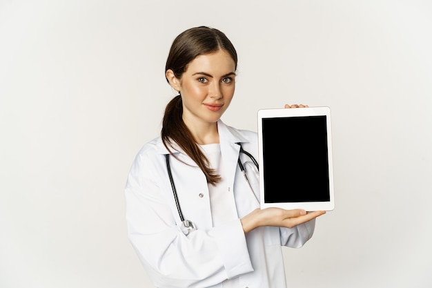 Bild einer ärztin im gesundheitswesen, die den digitalen tablet-bildschirm einer medizinischen online-website zeigt ...