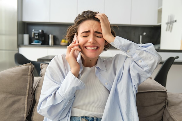 Bild einer frustrierten Frau beim Telefonieren, die während eines Telefongesprächs schlechte Nachrichten hört, sitzt bei ho
