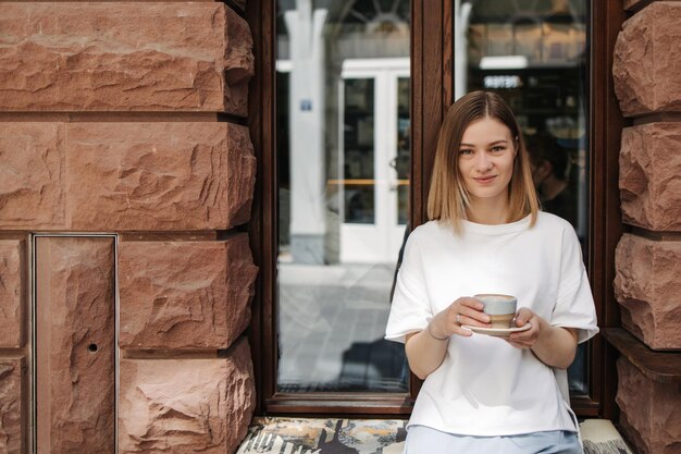 Bild einer hübschen Frau, die in die Kamera lächelt, die im Café sitzt