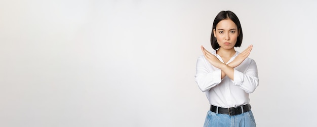 Kostenloses Foto bild einer jungen asiatischen koreanischen studentin, die ein stop-kreuz-verbotsschild zeigt, verbiete etw, die st