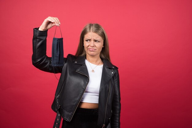 Bild einer jungen Frau, die eine schwarze medizinische Gesichtsmaske betrachtet