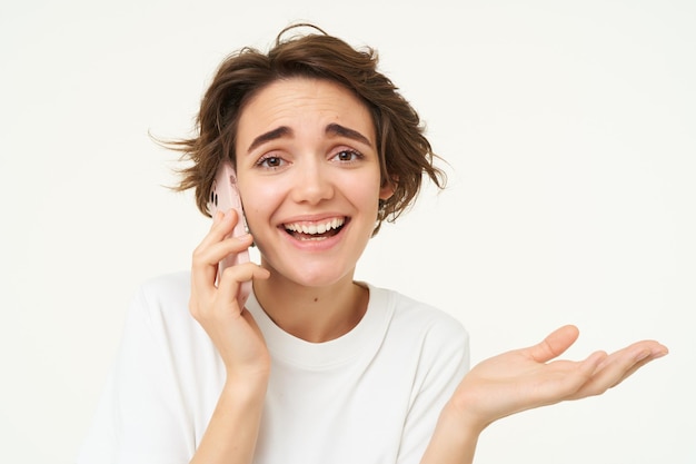 Kostenloses Foto bild einer lächelnden brünetten frau, die jemanden anruft, der mit einem mobiltelefon spricht und einen anruf entgegennimmt